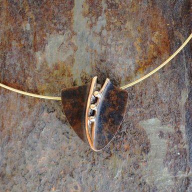 Bronzeanhänger auf Stein Ein trapezförmiger Anhänger mit goldenem Halsband