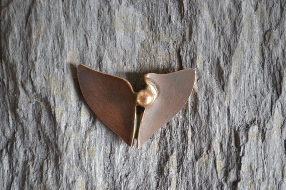 Brosche auf Stein Eine Brosche in Form eines Blattes mit einem perlenförmigen Kern liegt auf einem Stein