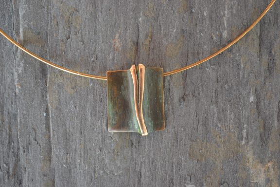 Grünspan auf Bronze Ein rechteckiger Anhänger mit Halskette, der Anhänger hat eine grünmlich schimmernde Oberfläche